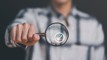 Businessman holding a magnifying glass, showing Audit Document concept