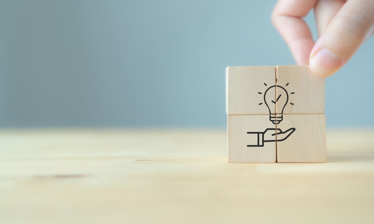 Hand puts the wooden cubes with light bulb on hand icon