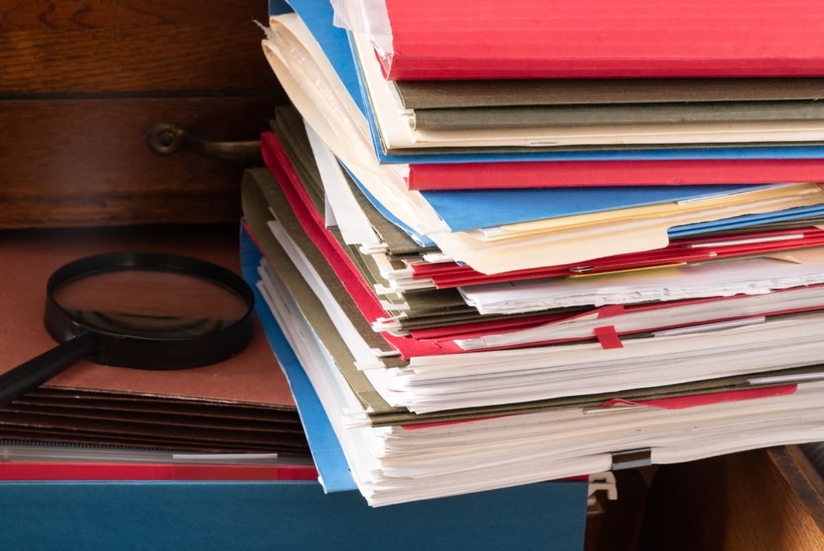 Stack of file folders and magnifying glass on an antique cabinet drawer